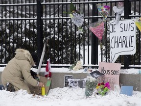 A man lights a candle as he pays his respects to shooting victims in Paris at a memorial set up outside the French Embassy in Ottawa on Thursday.