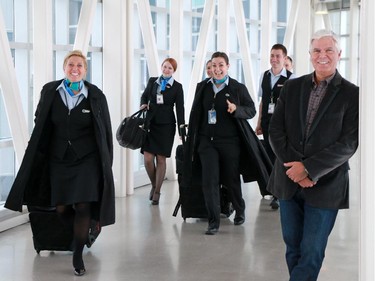 WestJet flight attendants walk past company CEO Gregg Saretsky at WestJet's Calgary headquarters on Tuesday Jan. 6, 2015.