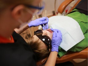 Dental Hygienist Christine Fairbairn examines nine year-old Emmanuel Kopp's teeth on the Alex Dental Health bus.