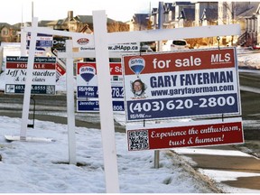 Real estate signs line Arbour Lake Road outside of the Arbour Lake Landing townhouse development on Thursday Jan. 22, 2015.