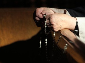 Addie Dedio prays with her rosary beads at Sacred Heart Church in Calgary, Alberta on February 11, 2013.