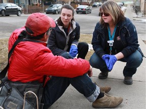 DOAP team outreach workers Chelsea Houston, left, and Jill Kirk try to convince a man to go to hospital for stitches after he fell and cut his face in Bridgeland. A study done by Alpha House on the Downtown Outreach Addiction Partnership Team shows the initiative saves the system nearly $10 for every dollar spent.
