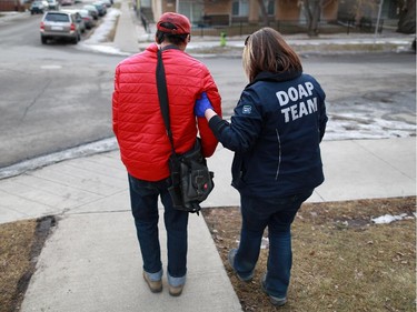 DOAP team outreach worker Jill Kirk helps a man after he fell and cut his face in Bridgeland. When the man, who was very unsteady on his feet, refused any medical help, the team took him home, with a promise to check on him later.