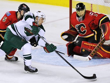 Calgary Flames defensemen Mark Giordano and Minnesota Wild Zach Parise fight for control in front of Jonas Hiller during the third period of NHL action at the Scotiabank Saddledome on Thursday Jan. 29, 2015. The Wild won the game 1-0.