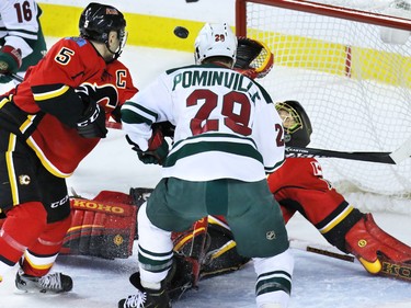 Calgary Flames goaltender Jonas Hiller looks to get a glove on a wild bouncing puck as defenceman Mark Giordano and Minnesota Wild forward Jason Pominville  fight for position during the first period of NHL action at the Scotiabank Saddledome on Thursday Jan. 29, 2015.
(Gavin Young/Calgary Herald)
(For City section story by Scott Cruikshank) Trax# 00057776A