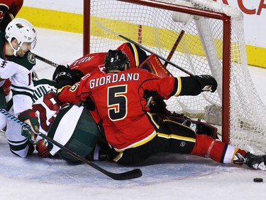 The Flames and Minnesota Wild pile up in front of Calgary Flames goaltender Jonas Hiller during second period NHL action at the Scotiabank Saddledome on Thursday Jan. 29, 2015.