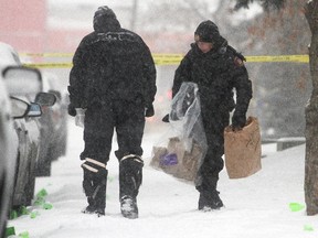 Calgary Police officers collect items amidst the numerous evidence markers Friday January 2, 2015, in front of the house where 7 people were shot early New Years morning.