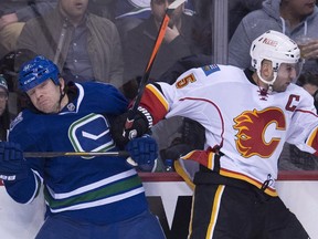 Calgary Flames defenceman Mark Giordano puts Vancouver Canucks right wing Derek Dorsett into the boards during Saturday's game.