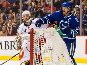 Calgary Flames defenceman Deryk Engelland looks as Vancouver's Henrik Sedin knocks the puck into the net past goalie Joni Ortio with a high stick during the second period of Saturday's game. The goal didn't count and the Flames won 1-0.