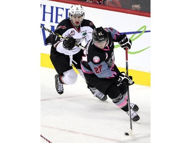 Calgary Hitmen defenceman Ben Thomas skated to get away from Vancouver Giants centre Alec Baer during WHL action at the Scotiabank Saddledome on January 25, 2015. The Hitmen won the game 8-0.
