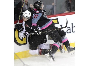 Calgary Hitmen centre Beck Malenstyn, right, drove Vancouver Giants defenceman Dmitry Osipov into the boards during WHL action at the Scotiabank Saddledome on January 25, 2015.