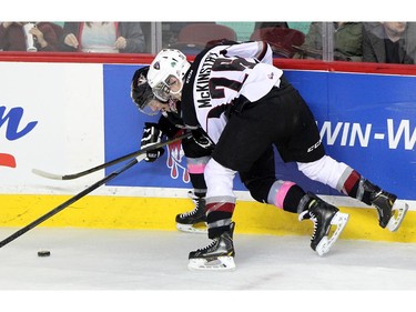 Calgary Hitmen left winger Elliott Peterson, left, tryed to escape the grasp of Vancouver Giants defenceman Ryely McKinstry as they fought for the puck along the boards during WHL action at the Scotiabank Saddledome on January 25, 2015.