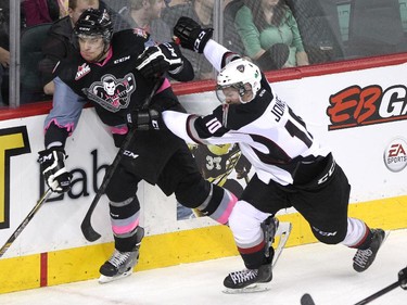 Calgary Hitmen defenceman Keegan Kanzig, left, and Vancouver Giants left winger Zane Jones battled for the puck along the boards during WHL action at the Scotiabank Saddledome on January 25, 2015.