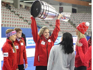 Team Canada skip Jennifer Jones, centre, hoisted the Grey Cup after it made an appearance with Stampeder players Rob Cote and Anthony Parker following a fun exhibition match to kick off the Continental Cup at the Markin MacPhail Arena at Winsport January 7, 2015.
