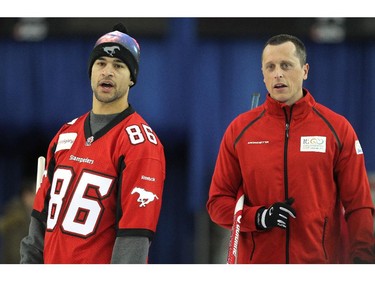 Team Canada curler E.J. Harnden, right, stood with Calgary Stampeders player Anthony Parker as they watched a shot during an fun exhibition match between teams Jennifer Jones and Brad Jacobs to kick off the Continental Cup at the Markin MacPhail Arena at Winsport January 7, 2015.