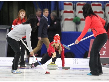 Canada curler Dawn McEwen, back left, watched as Canadian Olympian Chandra Crawford delivered the rock into the hands of her sweepers Olympic wrestler Carol Carol Huynh, left, and golfer Lisa "Longball" Vlooswyk on the ice during an fun exhibition match between Team Jennifer Jones and Team Brad Jacobs to kick off the Continental Cup at the Markin MacPhail Arena at Winsport January 7, 2015.