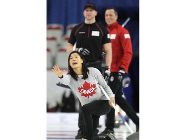 Canadian Olympic wrestler Carol Huynh, foreground, called to her sweepers as Team Brad Jacobs players Ryan Harnden and E.J. Harnden watched from behind her on the ice during an fun exhibition match between teams Jennifer Jones and Brad Jacobs to kick off the Continental Cup at the Markin MacPhail Arena at Winsport January 7, 2015.