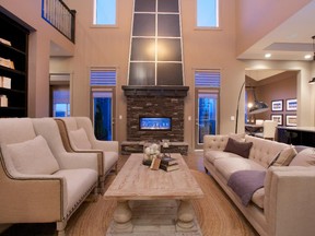 The great room in Homes by Avi's Waterford model features a towering fireplace surrounded in stone and flanked by windows.