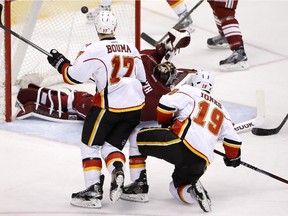 Calgary Flames' David Jones (19) scores against Arizona Coyotes' Mike Smith, sprawled on ice, as Flames' Lance Bouma (17) watches during the third period of an NHL hockey game Thursday, Jan. 15, 2015, in Glendale, Ariz. The Flames defeated the Coyotes 4-1.