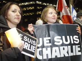 Marine Akel, left, and Mathilde Denier, both living in Calgary but from France, hold the "Je Suis Charlie" banner at a candlelight vigil held Wednesday evening January 7, 2015 on the Calgary City Hall steps commemorating the 12 people murdered in the terror attack in Paris.