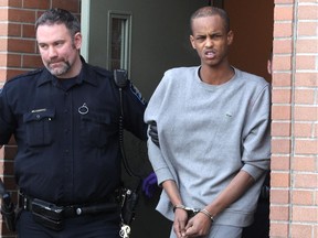 A suspect, right, in the Jan. 1 Killarney shooting was taken into custody on Thursday afternoon. He was photographed being escorted out of the Calgary Police Arrest Processing Unit by Sheriffs en route the Calgary Remand Centre on January 9, 2015.