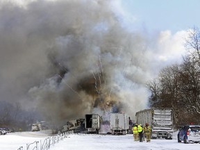 Emergency personnel watch as fireworks ignite at the scene of a fiery crash that closed both sides of Interstate 94, Friday, Jan. 9, 2015, near Galesburg, Mich.