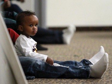 A boy sits with his father as he listens to a meeting held at the Abu Bakr Musallah Mosque on Saturday evening January 10, 2015. The meeting was held to help find ways to counter recent violence within the Somali community.