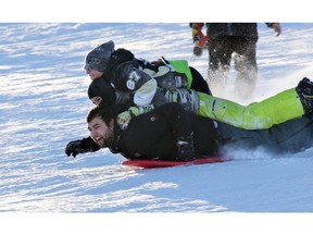 From top, Seth Belzale, Jeremy Switzer and Jamie Harrison, go for a triple decker ride in the fresh snow on the toboggan hill in St. Andrew's Heights on Sunday.