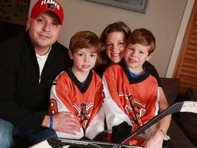 Diego and Jenn Rodriguez sit with their sons Bennett, left, and Mason in their Calgary home. Mason is back playing hockey after beating Stage 4 cancer last year.
