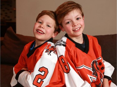 Minor hockey players and brothers Mason, left and Bennett pose in their hockey jerseys in their Calgary home. Mason is back playing hockey after beating stage 4 cancer last year.