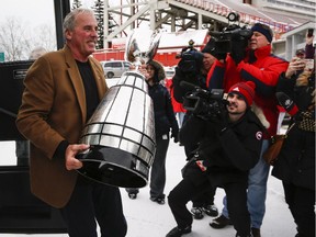 Calgary Stampeders head coach John Hufnagel carries the Grey Cup upon returning to Calgary after winning the 2014 CFL championship. On Wednesday, he was announced as one of three finalists for coach of the year.