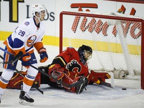 New York Islanders' Brock Nelson, left, skates away as Calgary Flames goalie Jonas Hiller, from Switzerland, picks himself up after letting in a goal during first period NHL hockey action in Calgary, Friday, Jan. 2, 2015.