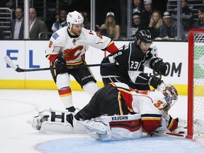 Calgary Flames goalie Joni Ortio reaches for the puck as Los Angeles Kings winger Dustin Brown skates towards it and Flames defenceman Dennis Wideman defends during Monday's game in L.A. Ortio has strung together four-straight wins for the Flames.