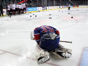 A dejected Regina Pat Canadians goalie Curtis Meger slumped on the ice as members of the Cariboo Cougars celebrated in the background after winning the Max's AAA Midget Tournament male final 2-1 in double overtime at the Scotiabank Saddledome on January 1, 2015.