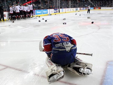 A dejected Regina Pat Canadians goalie Curtis Meger slumped on the ice as members of the Cariboo Cougars celebrated in the background after winning the Max's AAA Midget Tournament male final 2-1 in double overtime at the Scotiabank Saddledome on January 1, 2015.