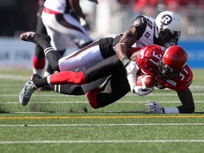 Calgary Stampeders receiver Jeff Fuller, right, is tackled by Ottawa's Jasper Simmons during an August game at McMahon Stadium. Simmons in now Fuller's teammate after being traded to Calgary on Thursday.