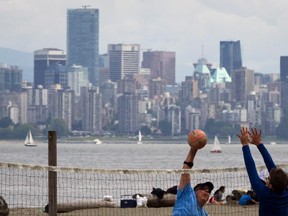 Men play volleyball at Spanish Banks Beach as downtown buildings tower above them in Vancouver B.C., on Monday May 20, 2013.