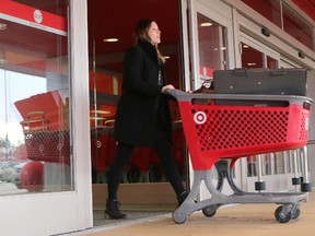 Melissa Brown pushes her loaded cart out the doors of the Market Mall Target store Thursday January 15, 2015, the day it was announced the company would be closing all it's Canadian outlets.