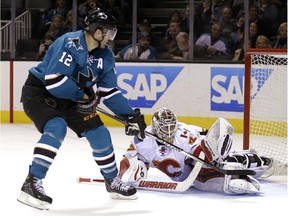 Calgary Flames' Joni Ortio, right, makes the save on a shot by San Jose Sharks' Patrick Marleau (12) during the third period of an NHL hockey game Saturday, Jan. 17, 2015, in San Jose, Calif. Calgary won 4-3 in overtime.