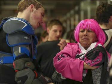 Loretta Hoblak, right, makes a face as she receives a (freshly used) pink jersey from her son, Brendan Hoblak, after the Northwest Calgary Athletic Associationís 5th annual ìPink in the Rinkî fundraiser in Calgary, on January 17, 2015.