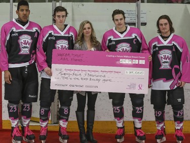 The Calgary AAA Flames captain and assistant captains present the $24,000 cheque to Canadian Breast Cancer Foundations Laura Reynolds after the Northwest Calgary Athletic Association's 5th annual "Pink in the Rink" fundraiser in Calgary, on January 17, 2015.