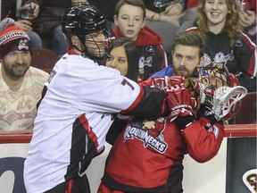 Roughnecks player Greg Harnett, right, takes a check to the neck from Vancouver Stealth's Tyler Digby during Calgary's National Lacrosse League home opener on Saturday.