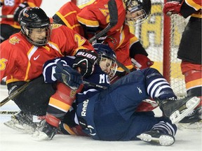 From right, The Mount Royal University Cougars' Tanika Dawson and the University of Calgary Dinos' Kitti Trencsenyi battle during their Crowchild Classic hockey game at the Scotiabank Saddledome in Calgary last February. The 2015 women's and men's doubleheader event is set for next Thursday.