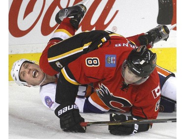 Joe Colborne of the Calgary Flames lands on top of Casey Cizikas of the New York Islanders behind the New York goal in the third period of the Flames 2-1 loss at the Saddledome Friday night January 2, 2015.