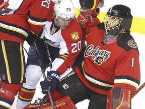 Calgary Flames goalie Joan Hiller is leaned on by Sean Bergenheim of the Florida Panthers, alongside teammate Derek Engelland during the first period at the Saddledome Friday night January 10, 2015.