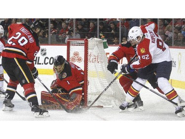 Calgary Flames goalie Jonas Hiller covers up the puck as Tomas Kopecky of the Florida Panthers tries to stuff it past during the second period Friday night January 10, 2015 at the Saddledome. Also on the play are Flames Derek Engelland, left, and Ladislav Smid.