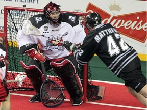 Calgary Roughnecks goalie Mike Poulin, left, defends the net against an effort by the Edmonton Rush's Mark Matthews during the first quarter of their NLL west final playoff game at the Scotiabank Saddledome in Calgary, Alberta Saturday, May 10, 2014.