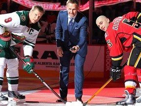 Former Calgary Flames forward Gary Roberts drops the puck with Minnesota Wild captain Mikko Koivu, left, and Calgary Flames captain Mark Giordano before their meeting at the Scotiabank Saddledome on Thursday night.