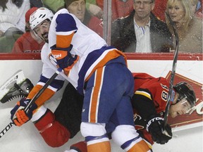 Matt Stajan of the Calgary Flames collides with Cal Clutterbuck of the New York Islanders along the boards during the second period at the Saddledome Friday night January 2, 2015.