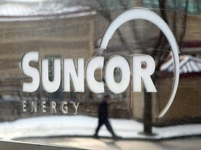 A pedestrian is reflected in a Suncor Energy sign in Calgary.